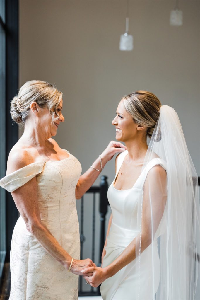 Bride and mother smile at eachother 
