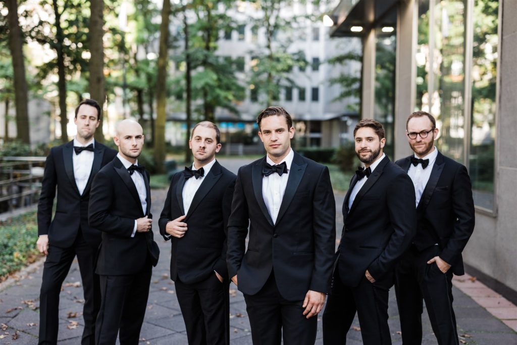 Groom and groomsmen pose together outside PPG