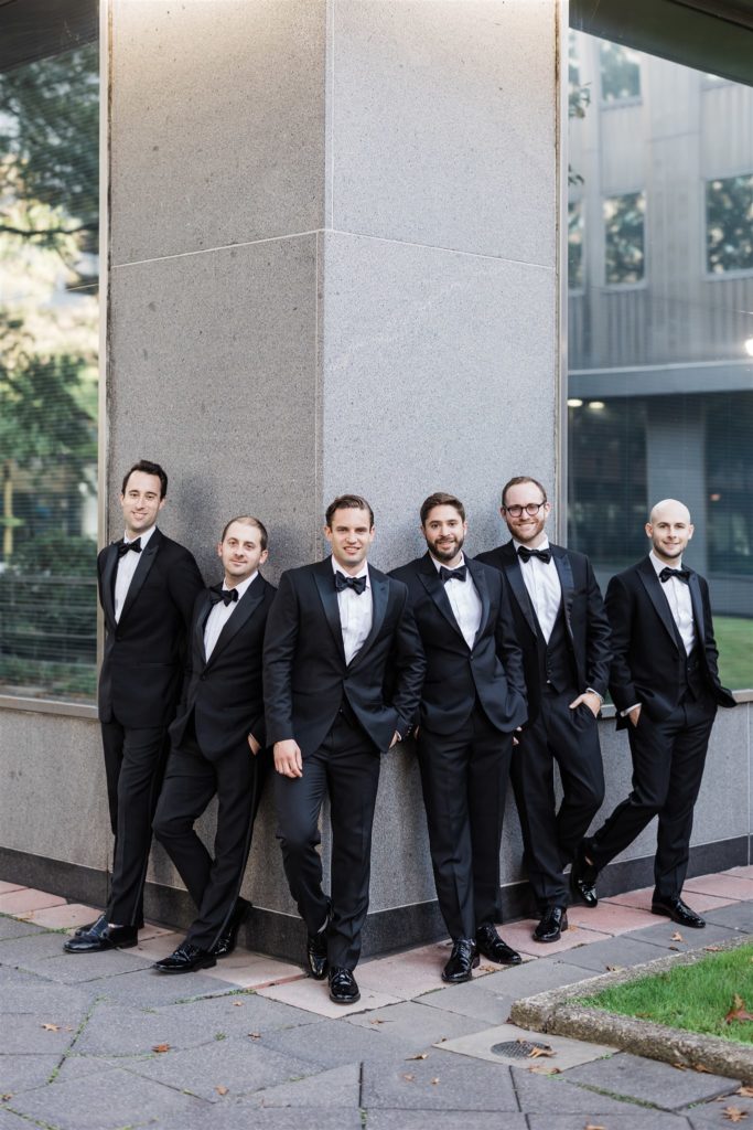 Groom and groomsmen pose together outside PPG