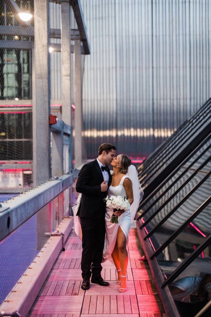Bride and groom kiss on the PPG rooftop at sunset
