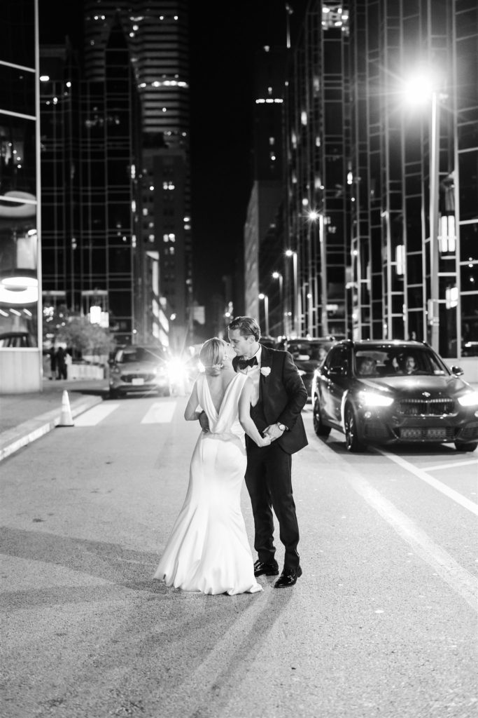 bride and groom kiss in the street next to the PPG Wintergarden 