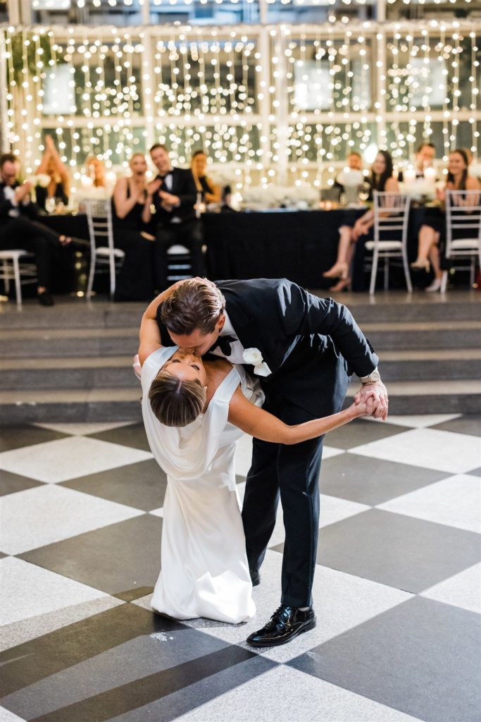 Groom dips bride and kisses her at black and white PPG Wintergarden wedding