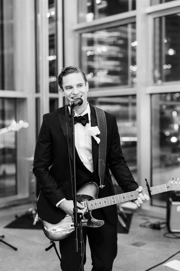 Groom smiles and plays guitar at black and white PPG wedding