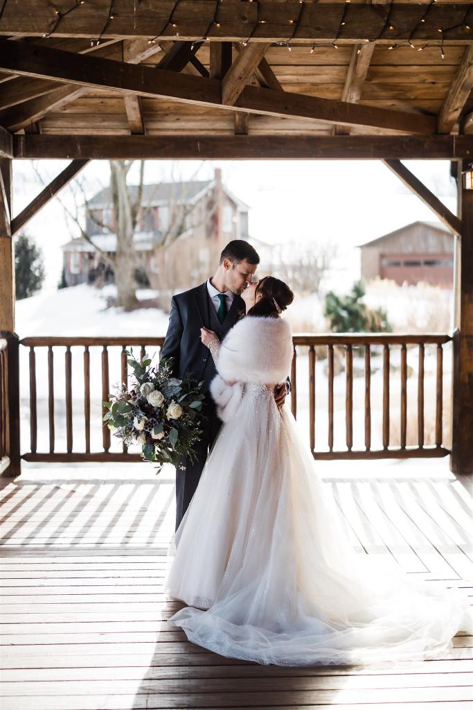 Bride and groom kiss on the porch at Armstrong Farms Winter Wedding