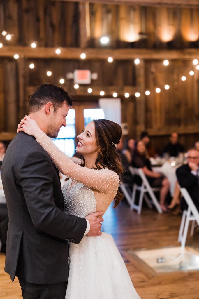 Bride smiles lovingly at groom during first dance at Armstrong Farms Winter Wedding