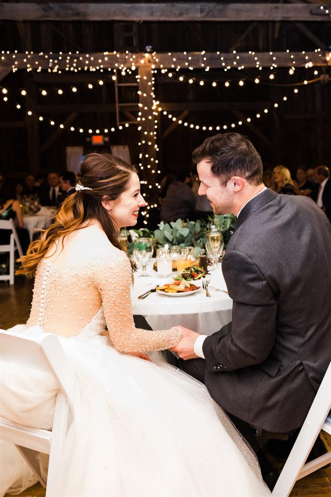 Bride and groom smile at each other at Armstrong Farms Winter Wedding reception