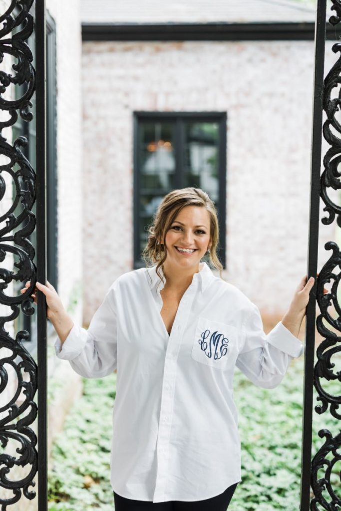 Bride smiles into camera wearing monogrammed white collared shirt