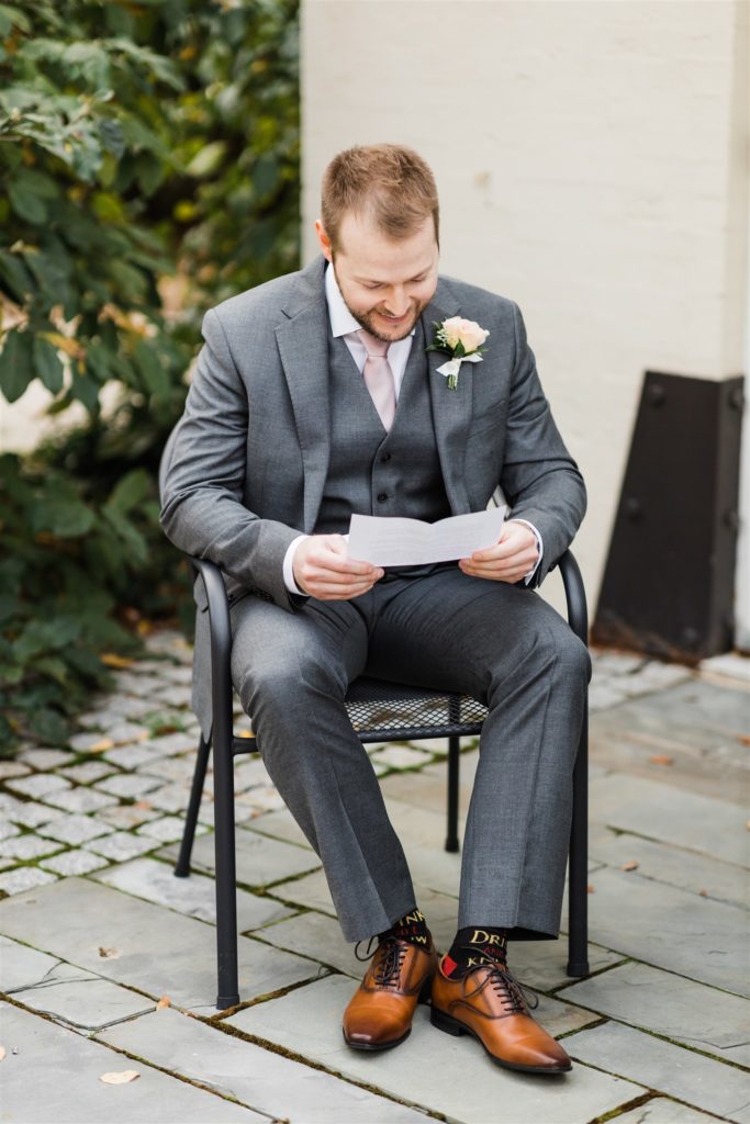 groom smiles as he reads a letter from his fiance