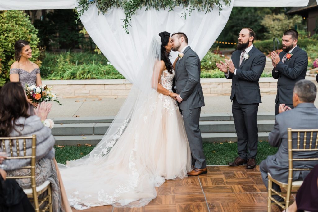 Bride and groom share their first kiss as husband and wife at their Fall Frick Pittsburgh wedding
