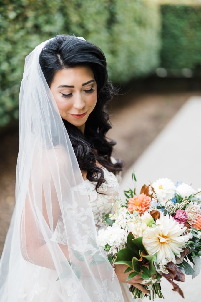 Bride smiles and looks down holding a colorful bouquet