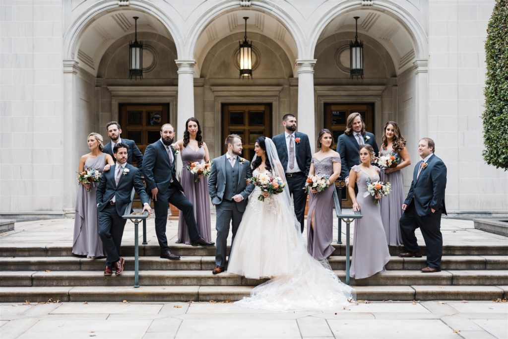 Bride and groom pose with bridal party in front of Frick Art museum 