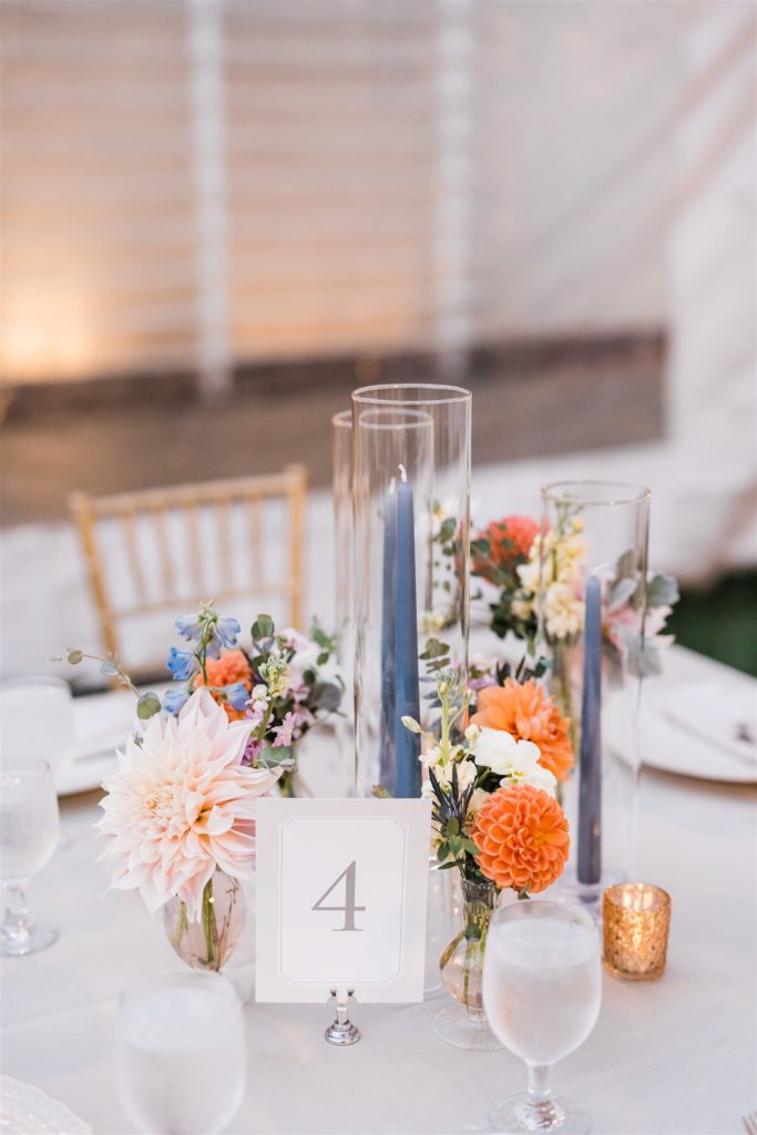 Candle centerpieces with orange, light pink and blue florals