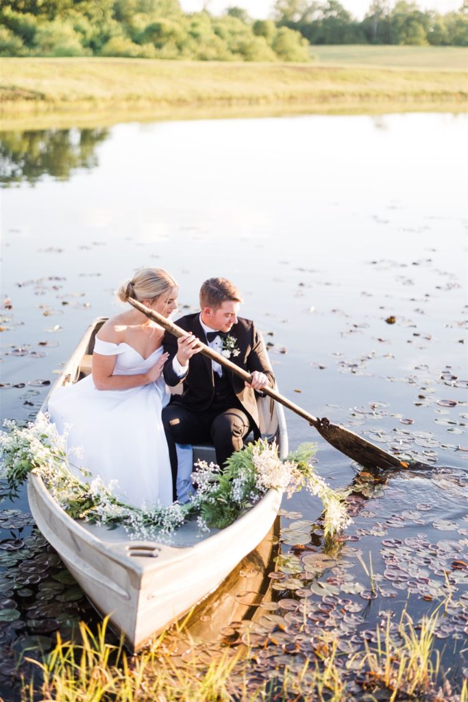 Bride and groom take photos in boat at White Barn lake