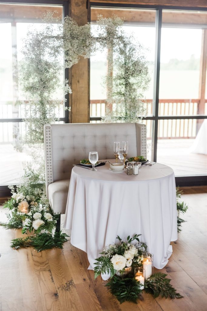 Sweetheart table with baby's breath and all white linens at wedding at White Barn