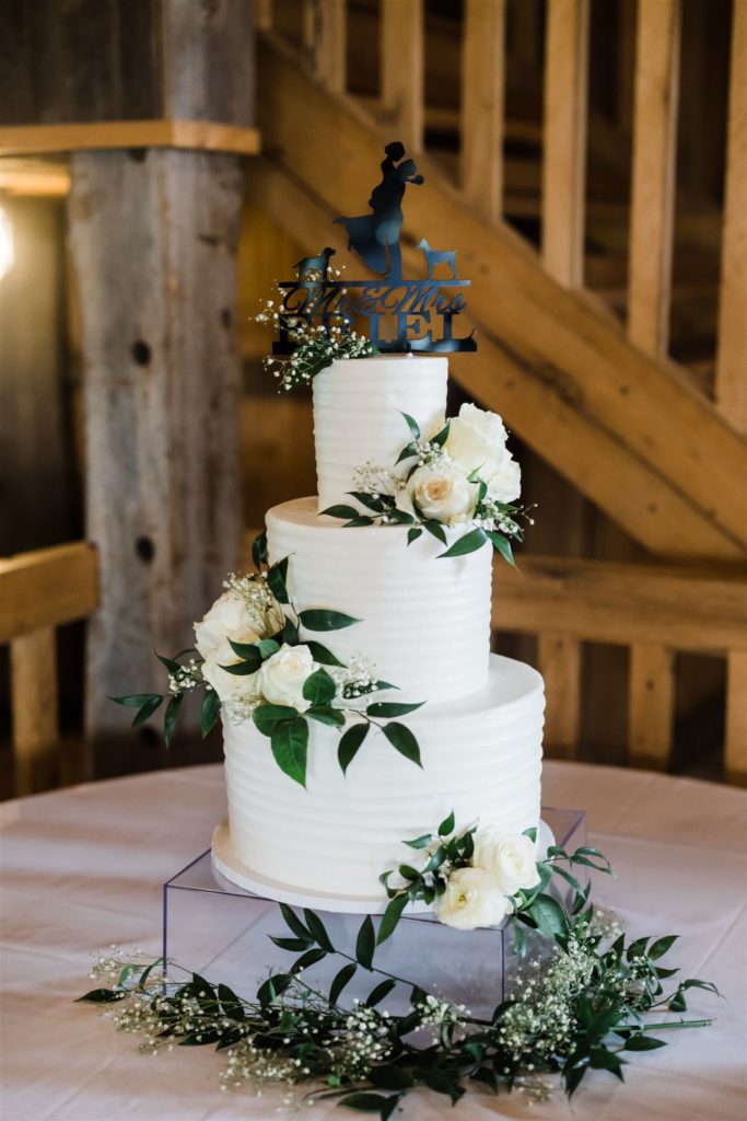 All white wedding cake with roses and greenery at White Barn wedding